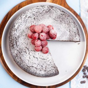 Keto Chocolate Cake topped with raspberries with a slice removed.