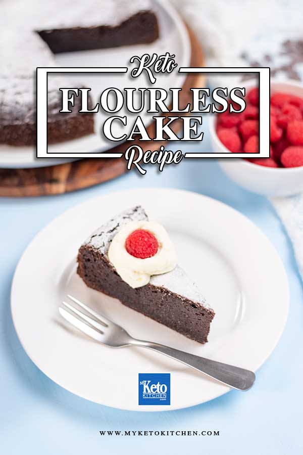 A sliced of Keto Flourless Cake on a plate topped with whipped cream and a raspberry.