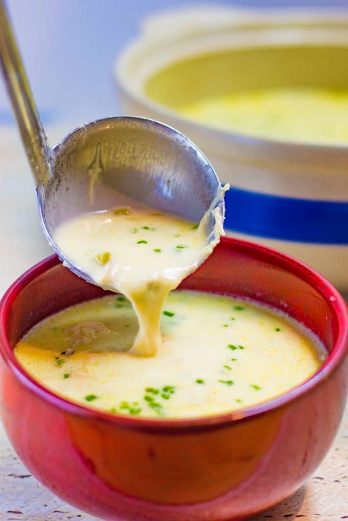 Keto cream of chicken soup being poured into a red soup bowl with a ladle.