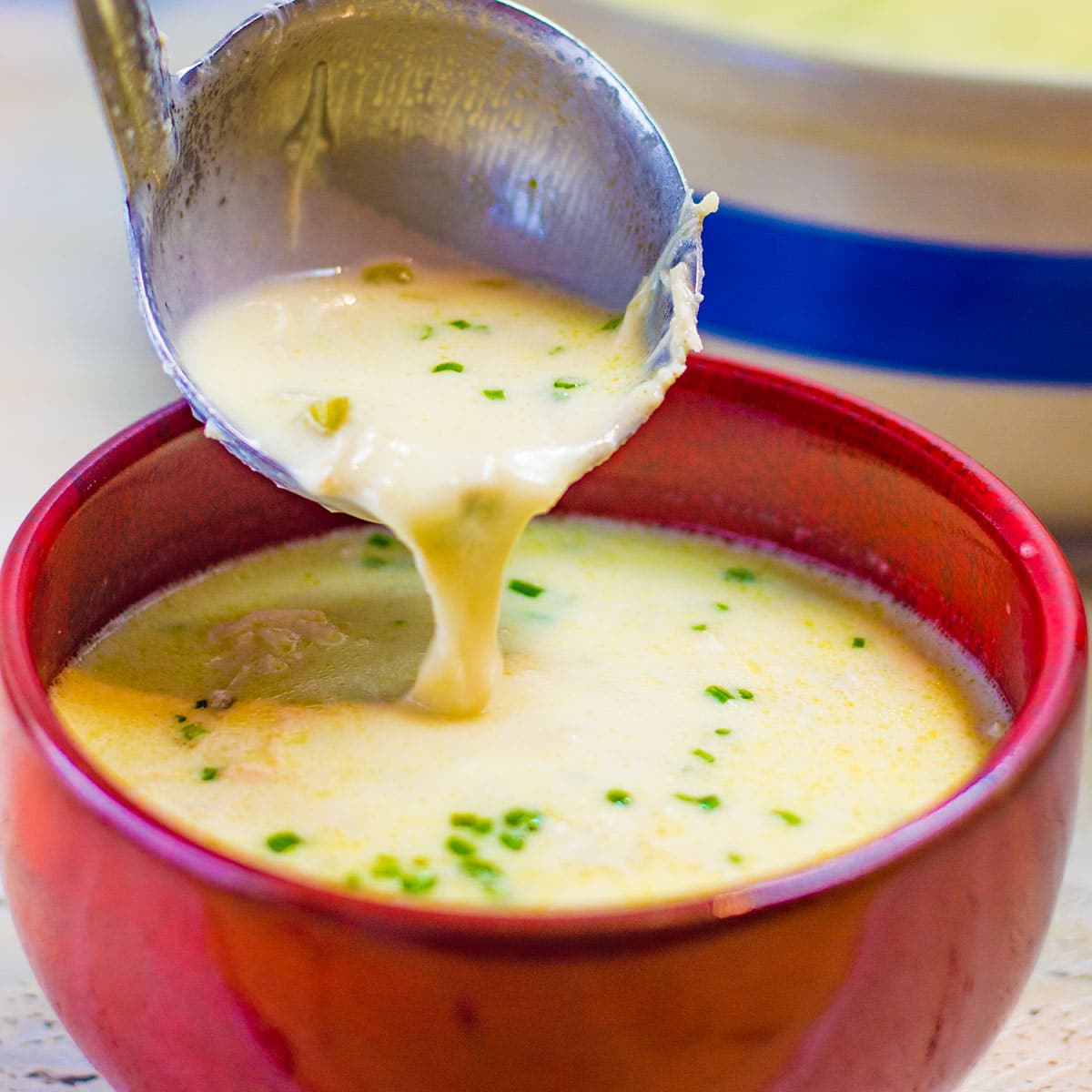 Keto cream of chicken soup being poured into a red soup bowl with a ladle.