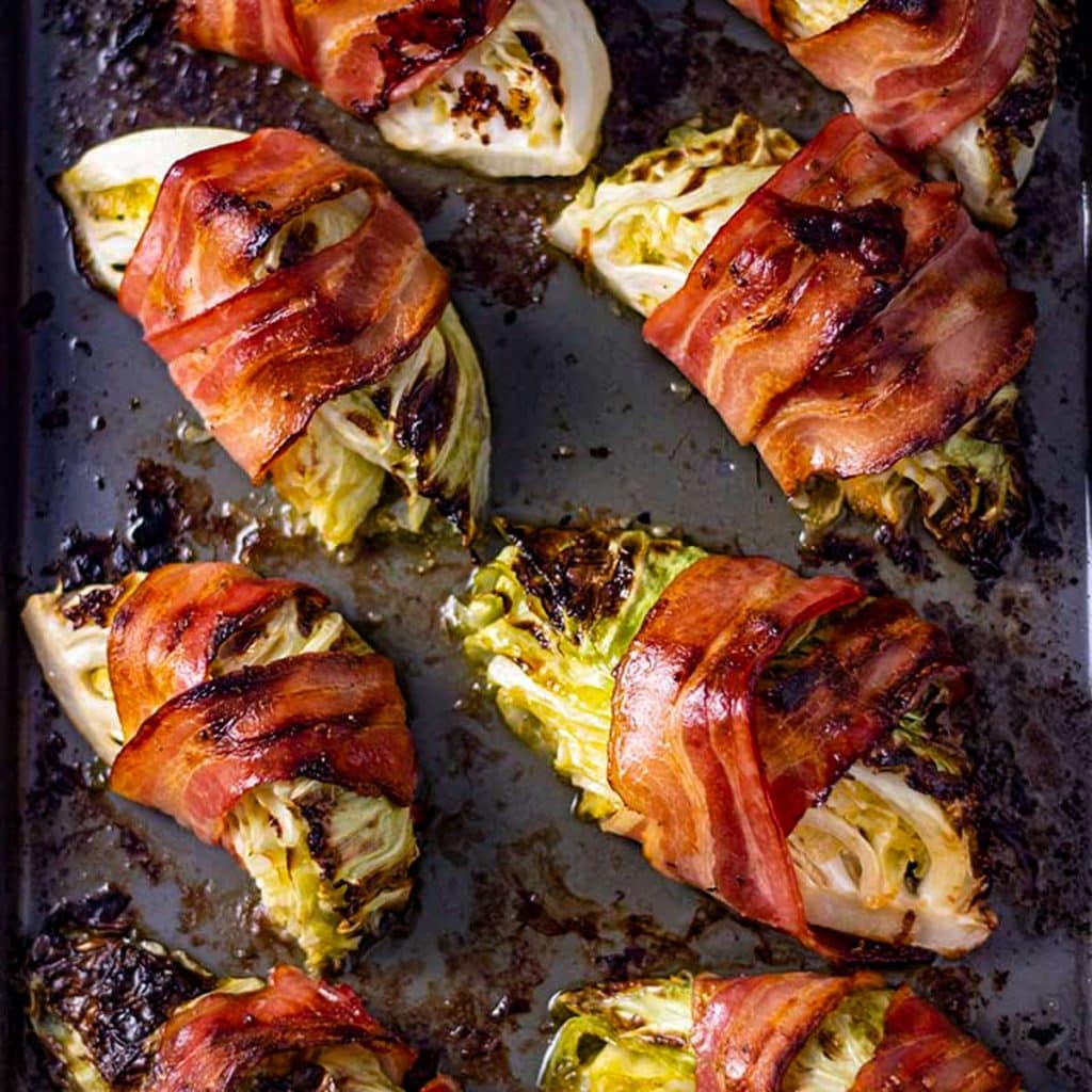 Bacon wrapped cabbage on a baking tray.