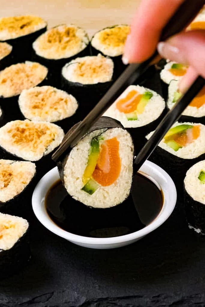 keto sushi roll being dipped in tamari sauce.
