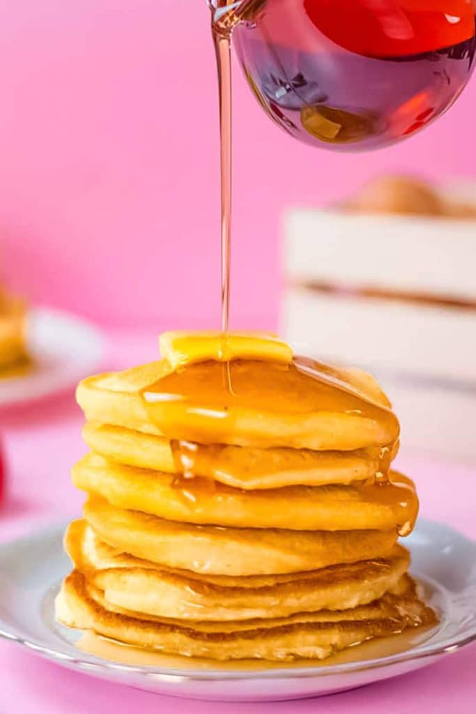 Keto pancake stack with maple syrup being poured over it.