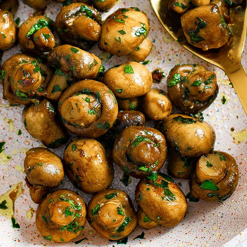 Garlic butter mushrooms on a white plate.