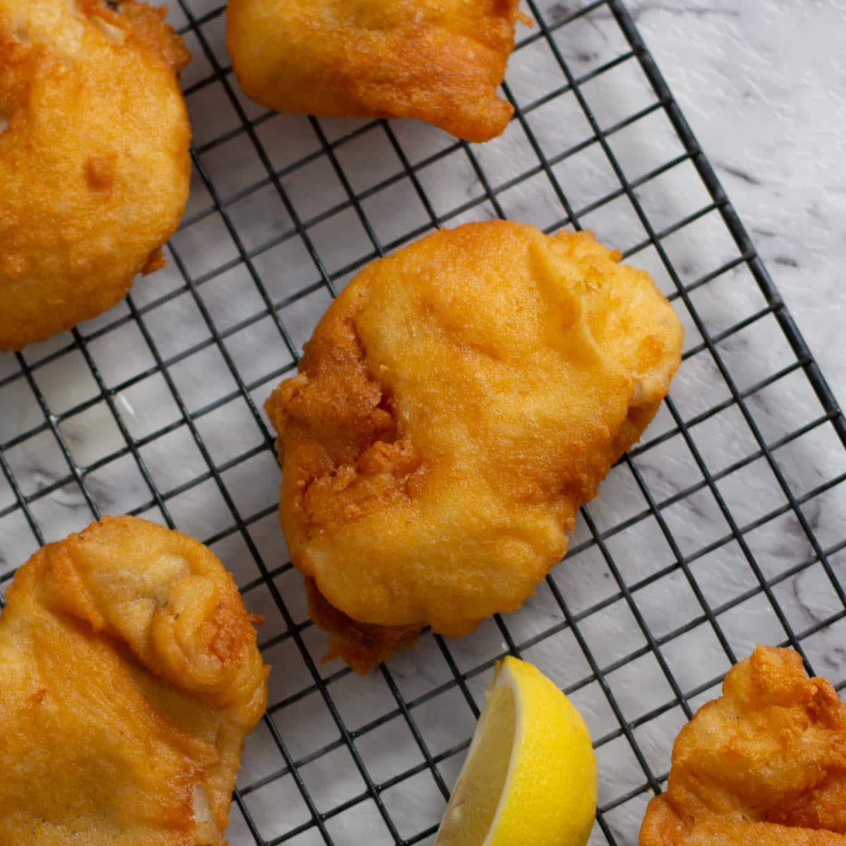 Keto batter over fish on a cooling rack.