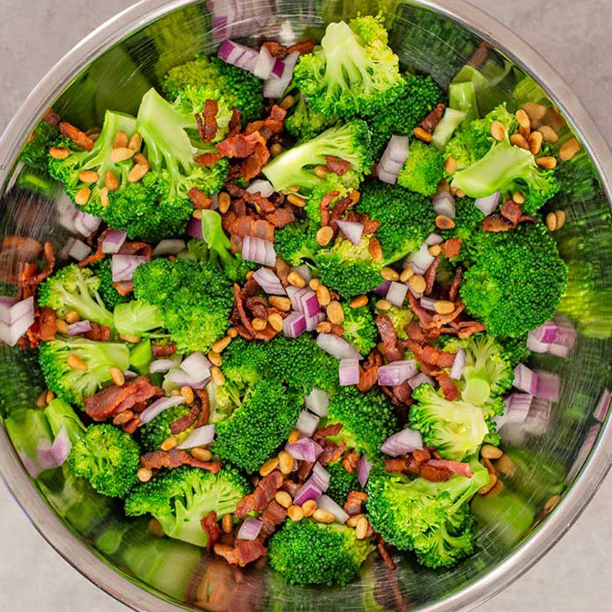 Broccoli and pine nuts in a mixing bowl.