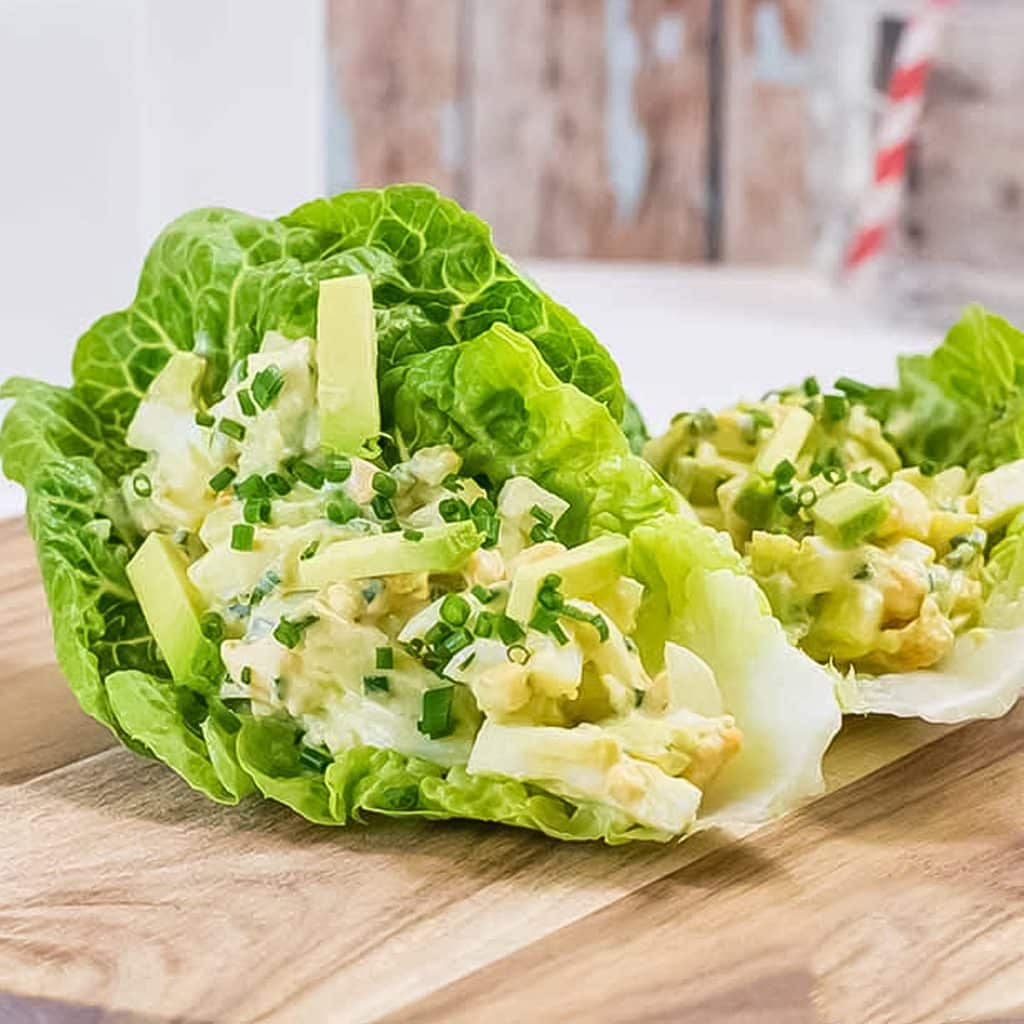 Keto egg and avocado lettuce wrap on a wooden board.