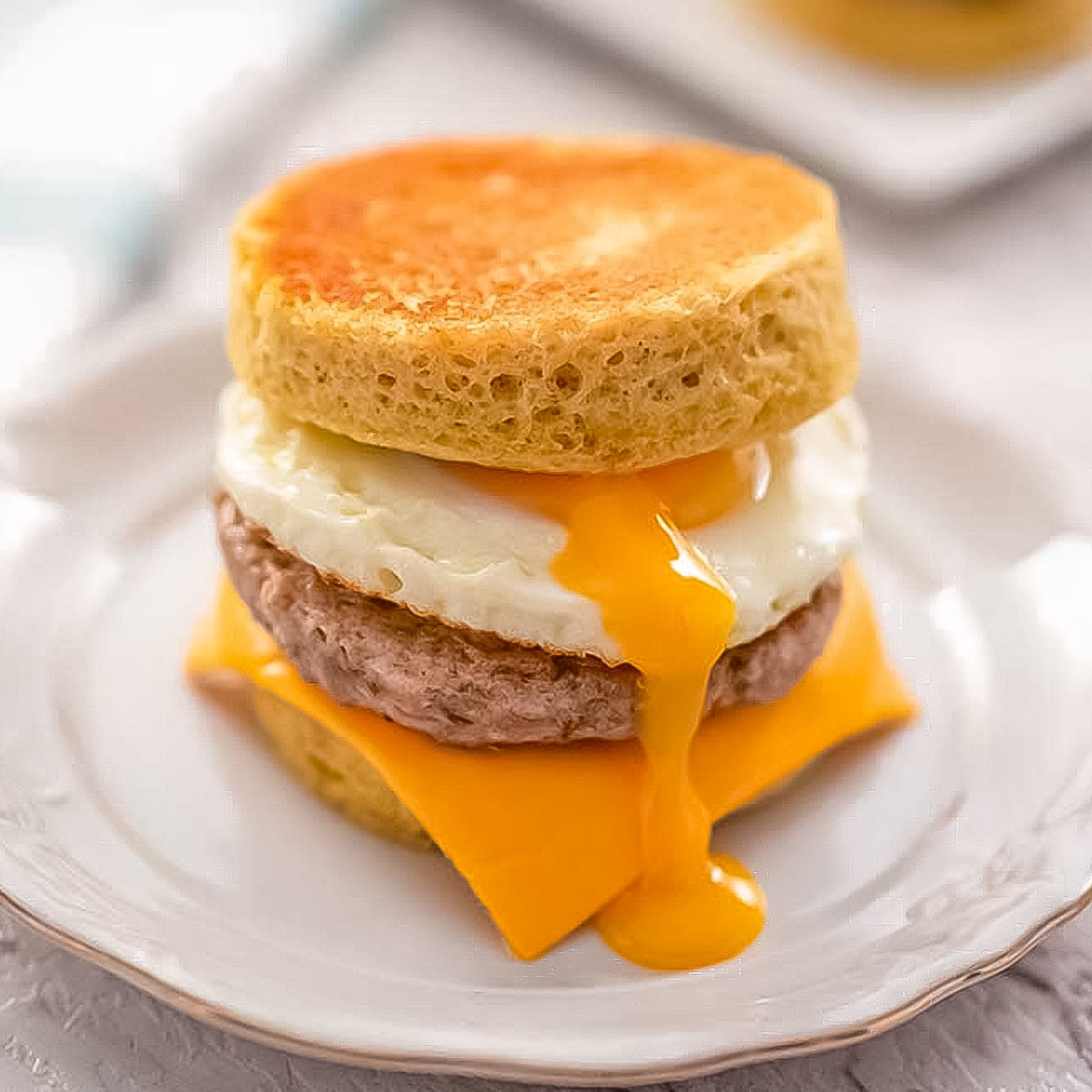 keto sausage and egg muffin on a white plate.