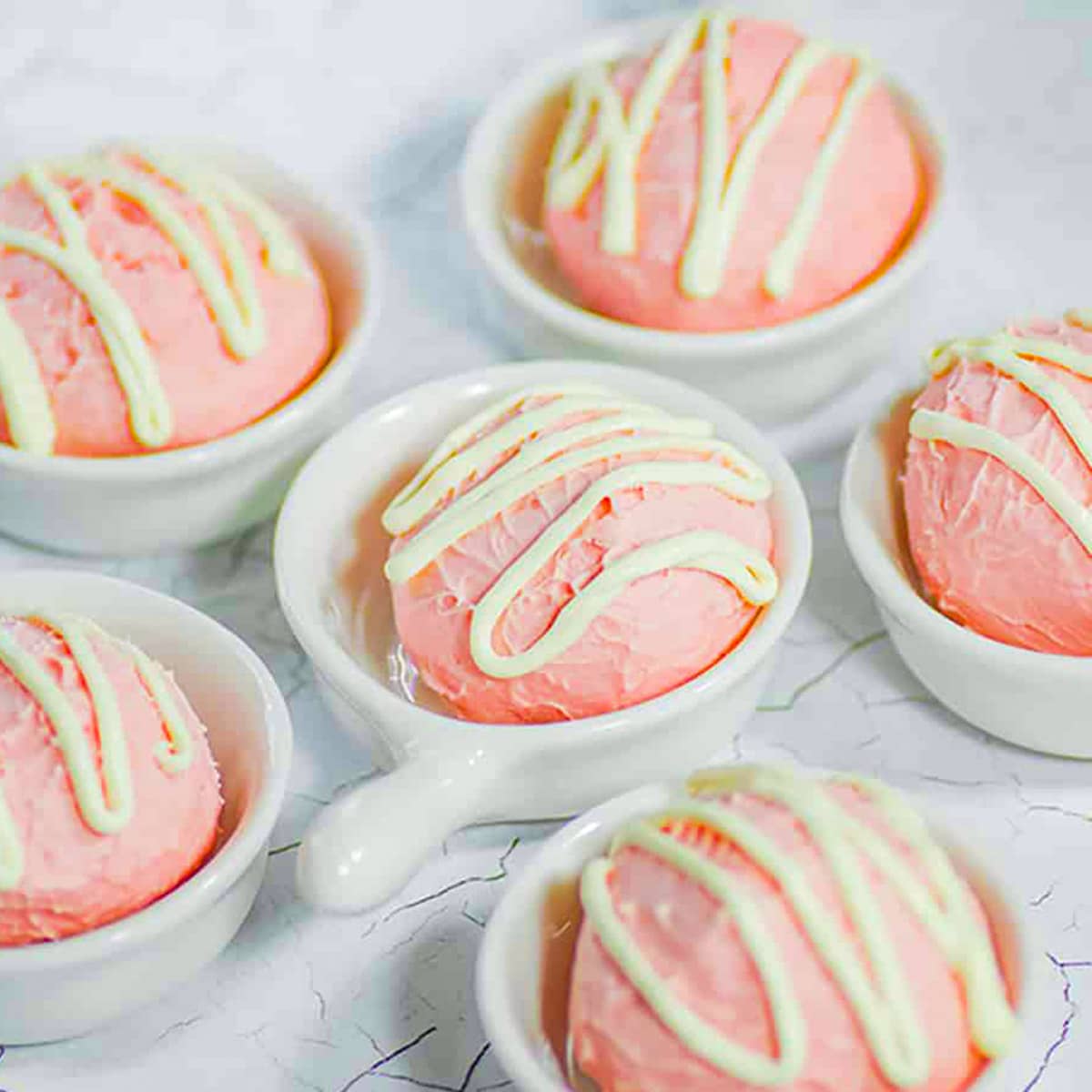 Keto strawberry fat bombs in white bowls.