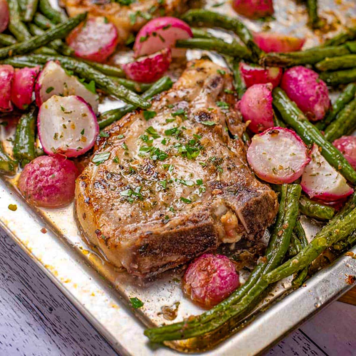 Keto pork chops on a plate with radish and green beans.