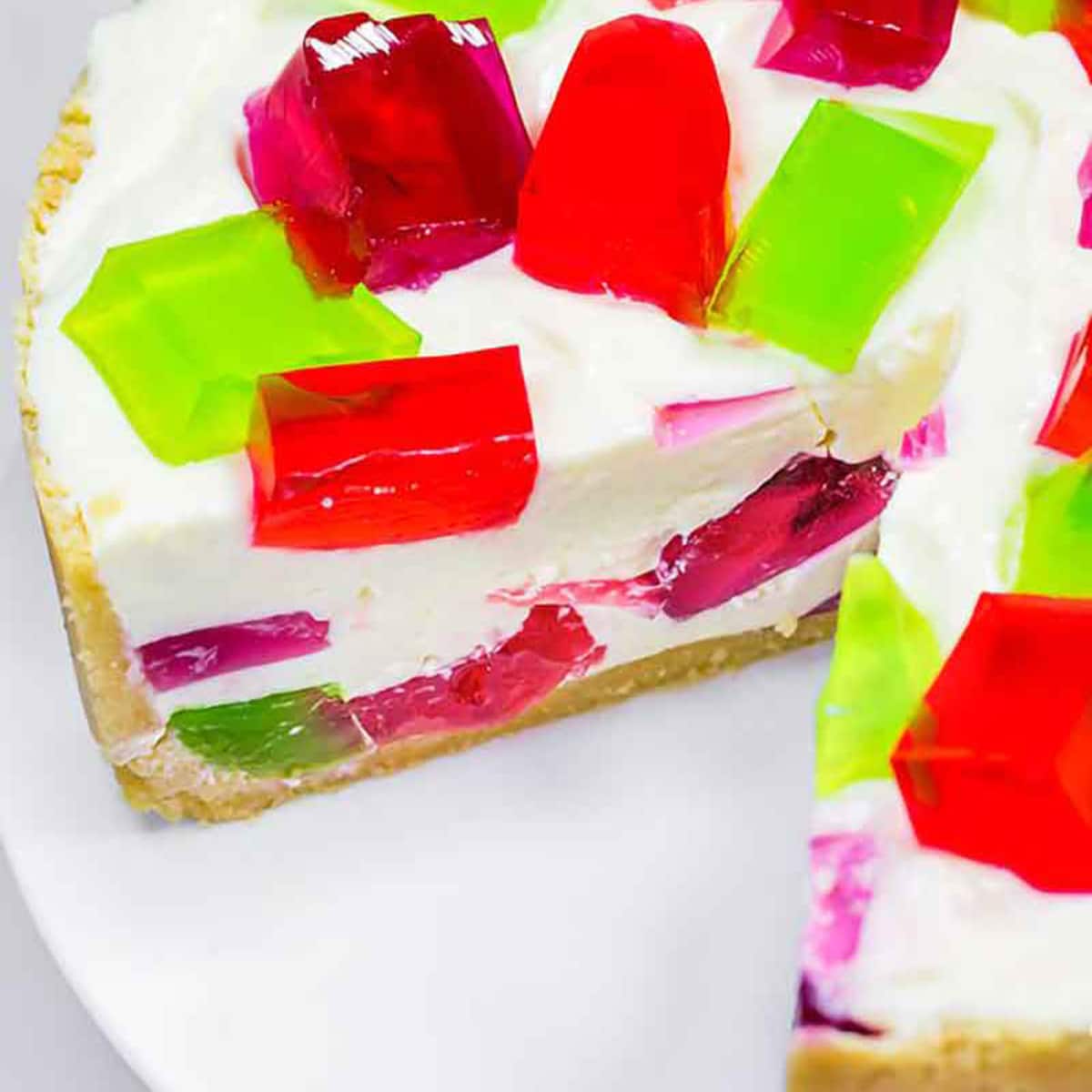 Keto jello cake with a slice missing on a plate.