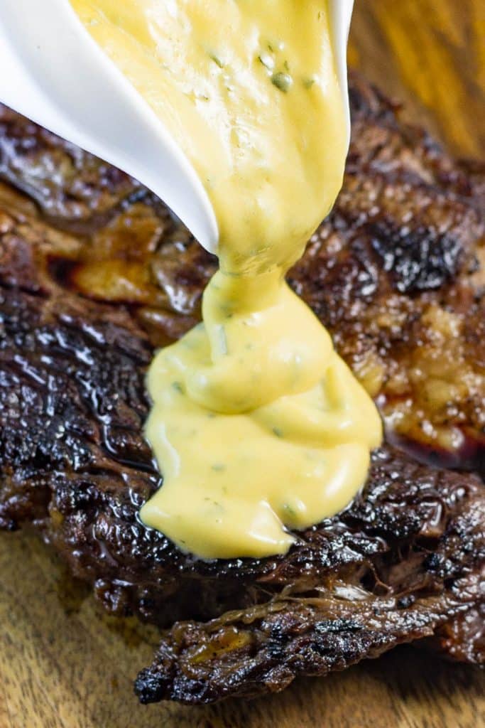 Keto bearnaise sauce being poured over a peice of steak.