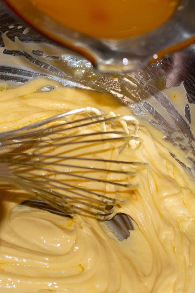 Bearnaise sauce being whisked in a silver mixing bowl.