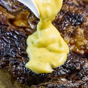 Keto bearnaise sauce being poured over a cooked steak.