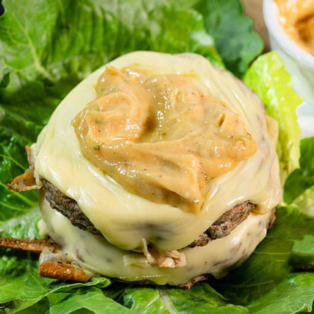 keto burger sauce on a beef patty with cheese over a lettuce bed.