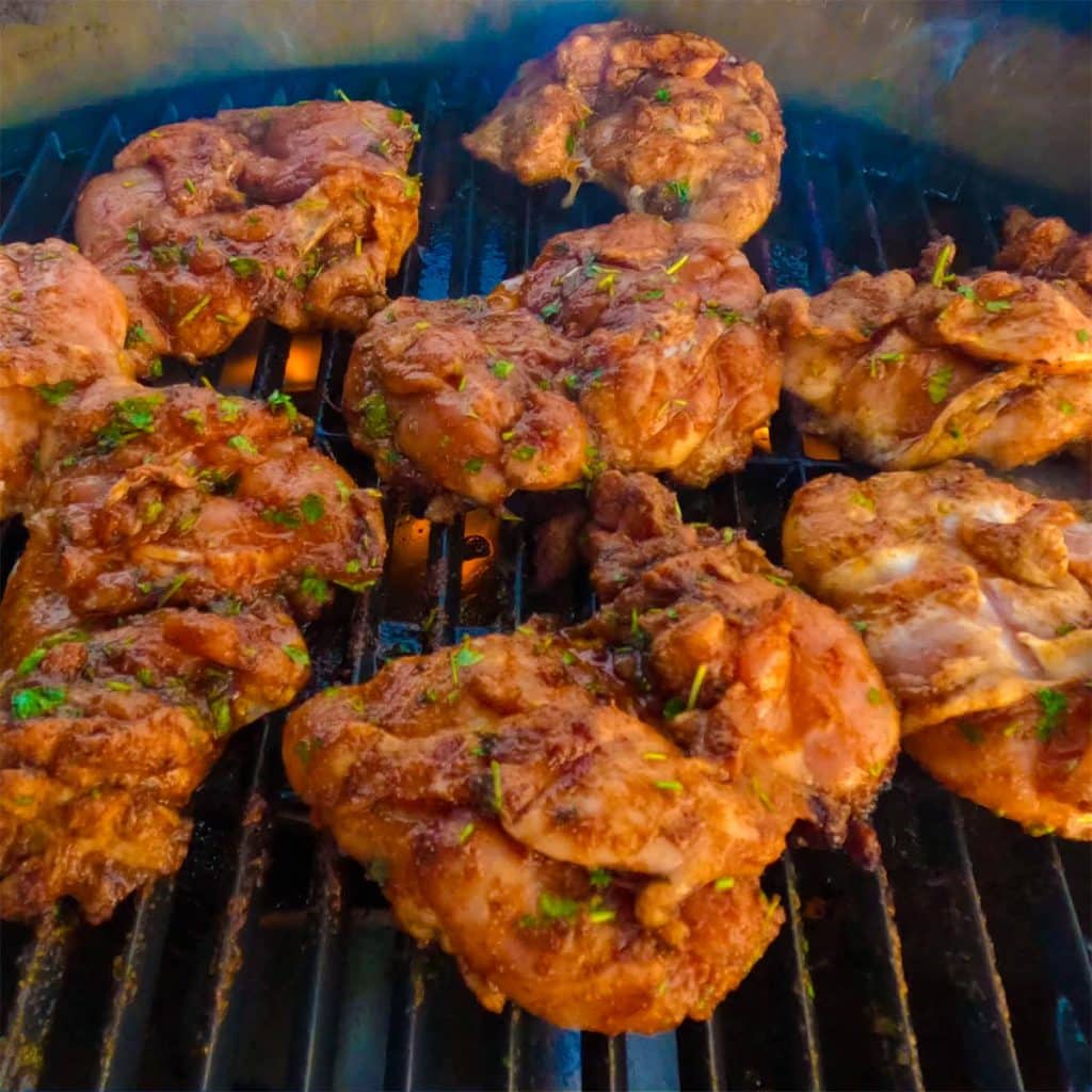 Chicken thighs cooking on a grill.
