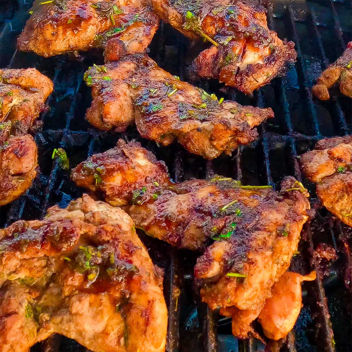 Flame grilled keto chicken thighs on a BBQ grill.