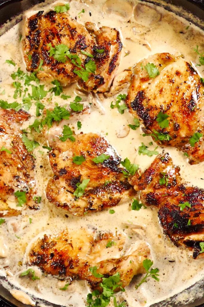 Boneless chicken thighs with mushroom and garlic sauce in a cast iron frying pan.